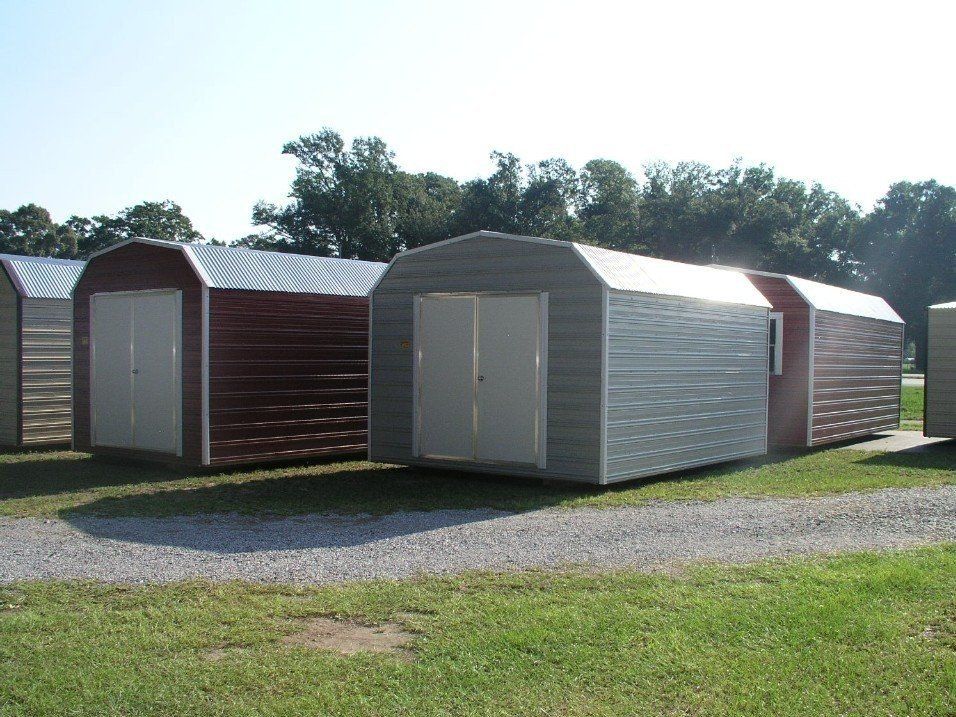 A row of sheds are lined up in a grassy field