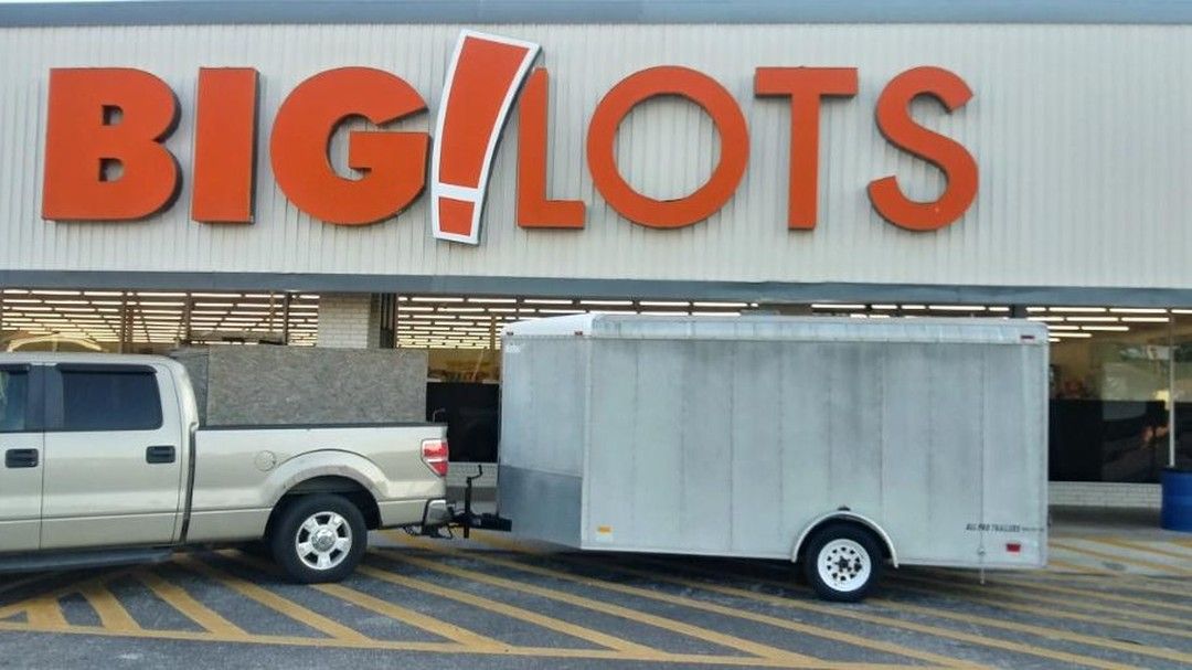 Modern office with desks, chairs, computers, and large windows. Sunlight streams in.