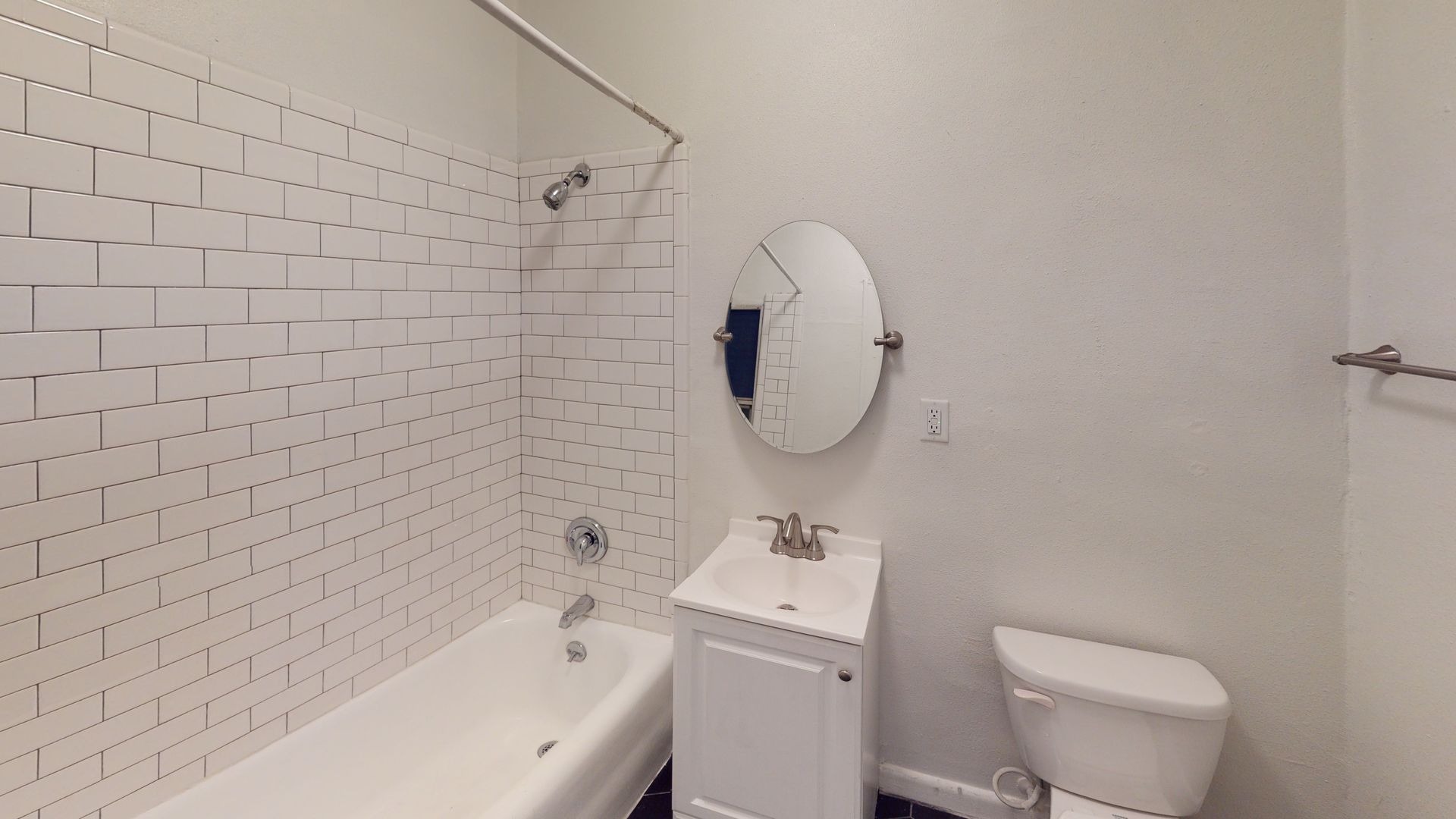 Bathroom with white brick tile, a tub, sink, mirror, and toilet.