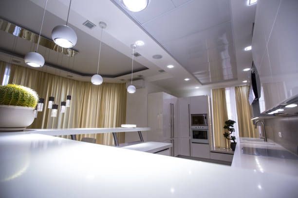Modern white kitchen with round pendant lights, a cactus, and white cabinets.