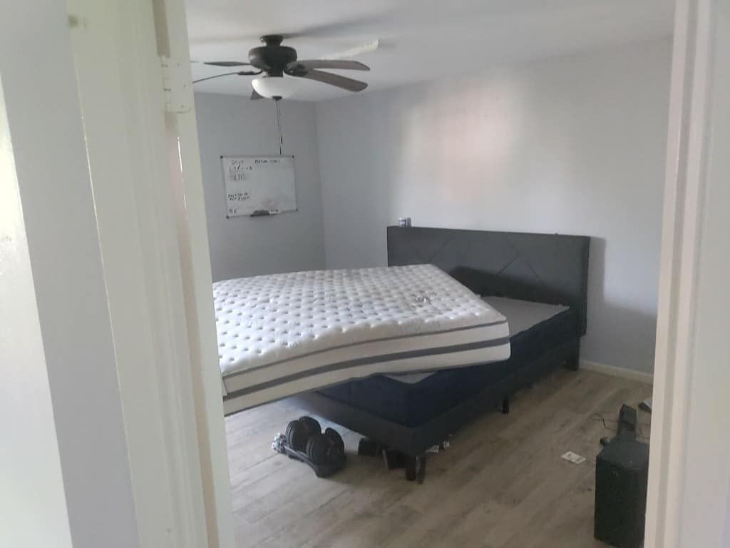 A bedroom with a mattress on top of a bed and a ceiling fan.