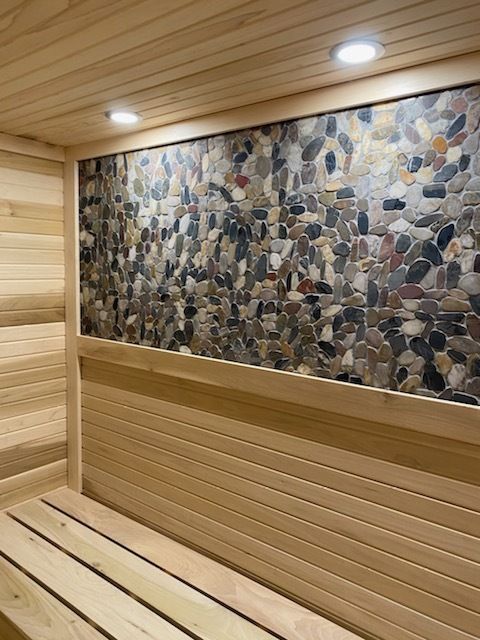 A wooden sauna with a stone wall and a bench.