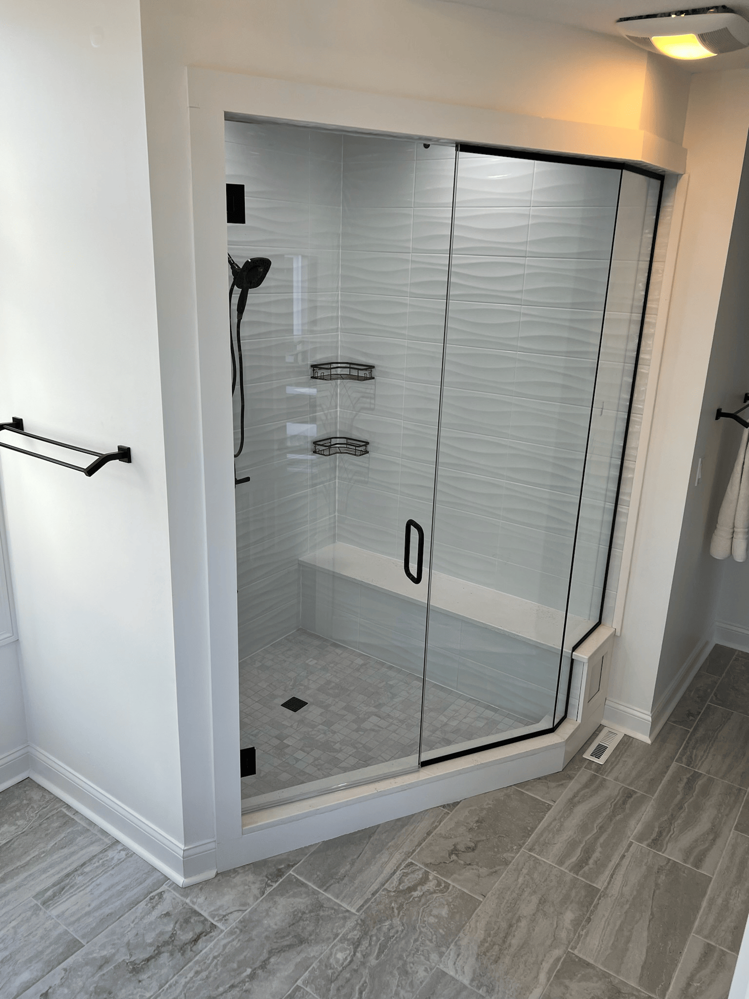 A bathroom with a walk in shower with a glass door.