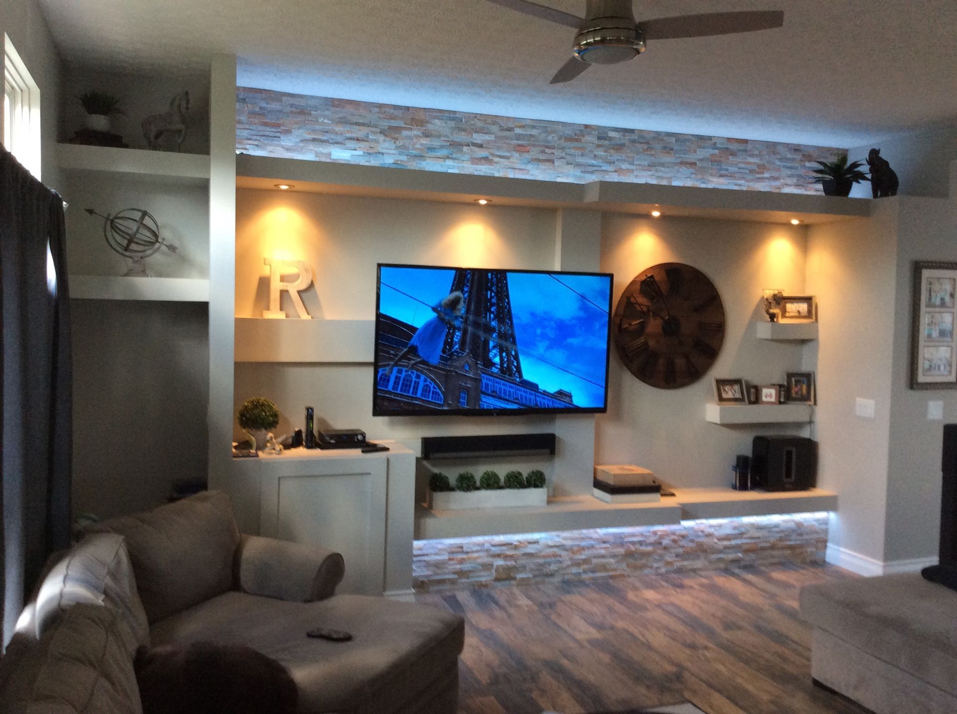 A living room with a flat screen TV and a ceiling fan.