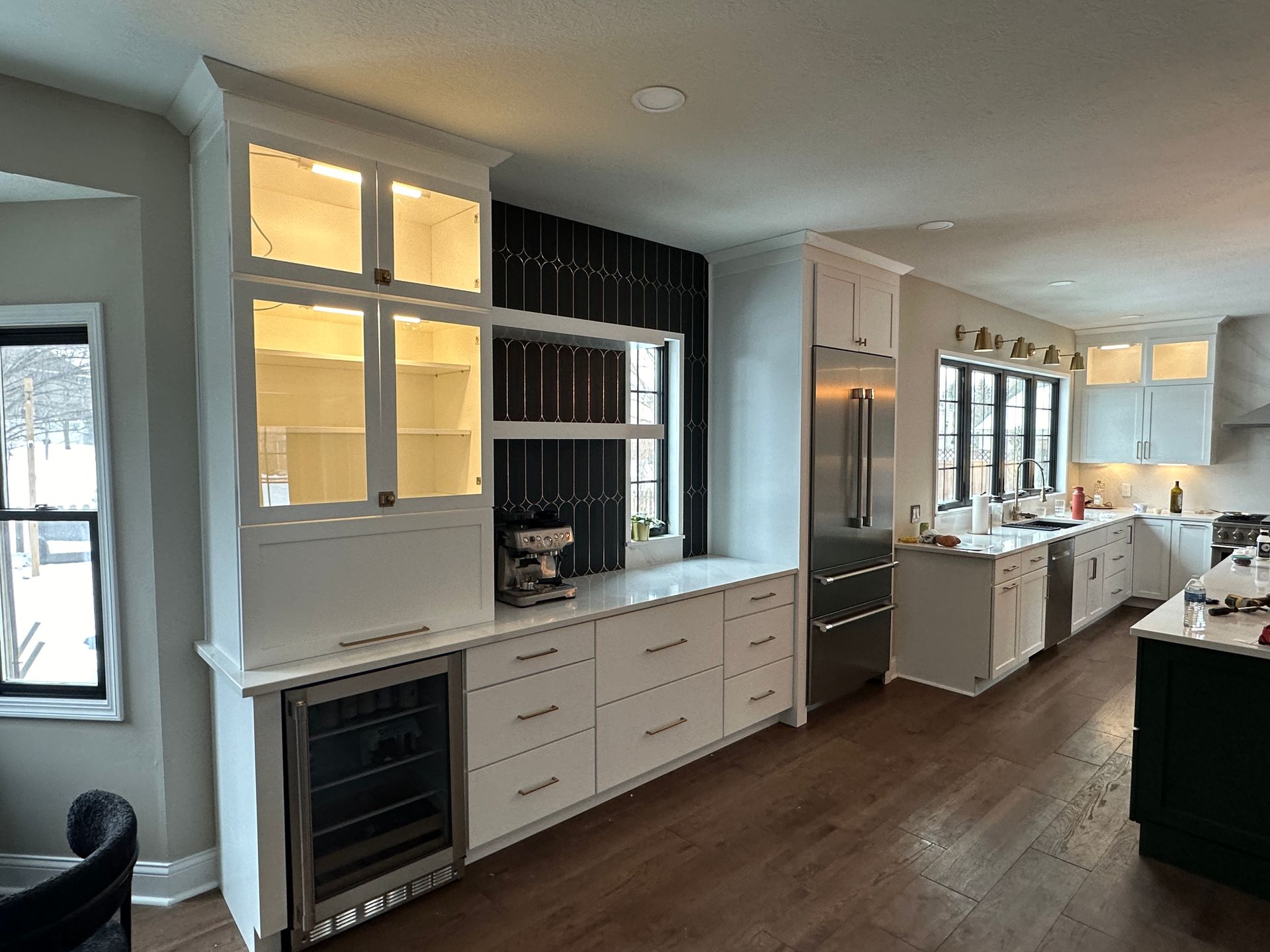 A kitchen with white cabinets , stainless steel appliances , a refrigerator and a wine cooler.