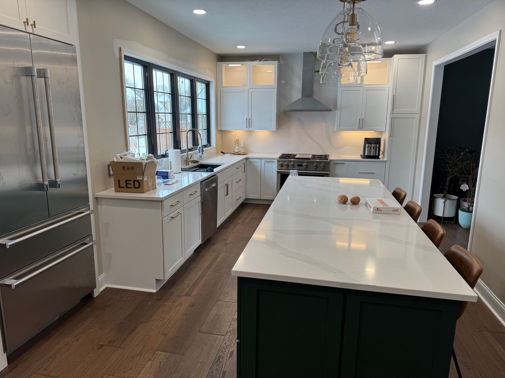 A kitchen with white cabinets , stainless steel appliances , and a large island.