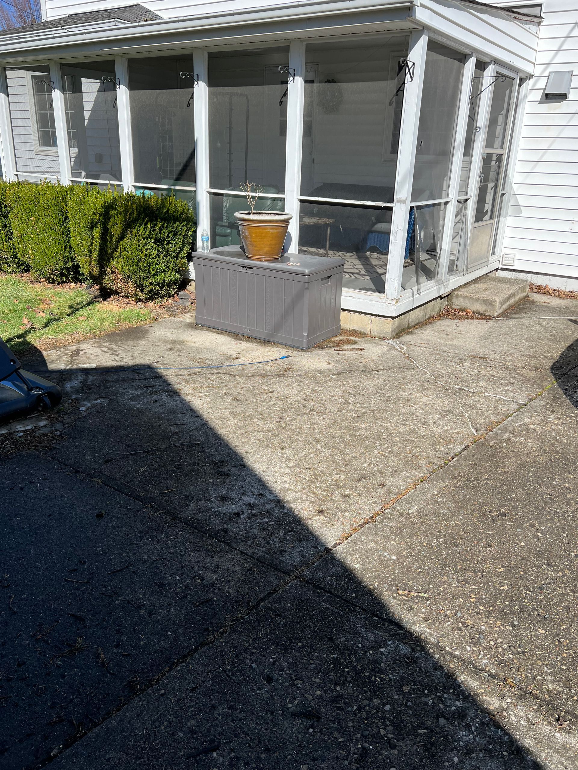 A screened in porch with a potted plant in front of it.