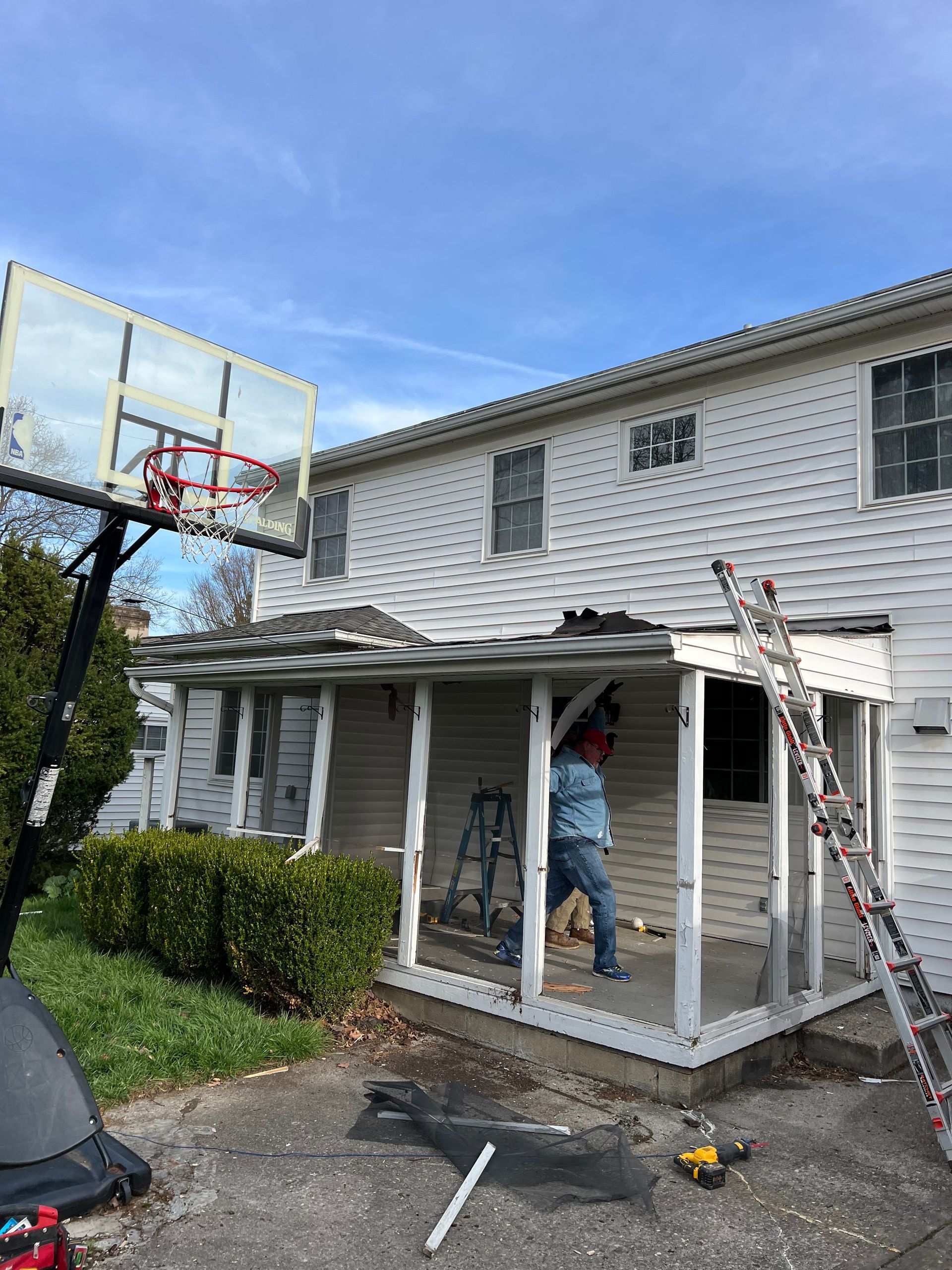 A man is standing on a porch next to a basketball hoop.