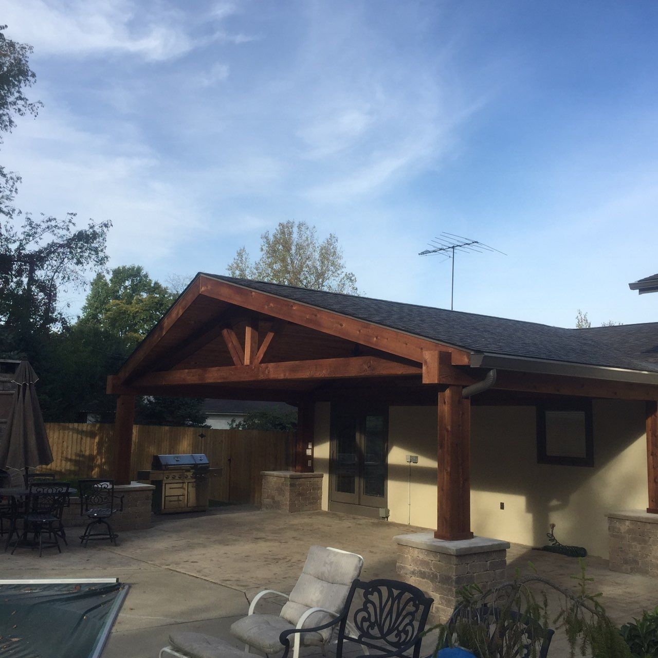 A wooden deck with a black railing and a wooden roof.