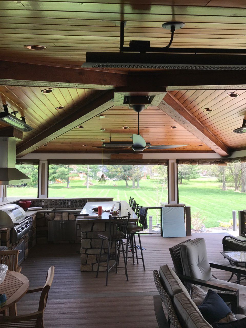 A large covered patio with a kitchen and a ceiling fan.