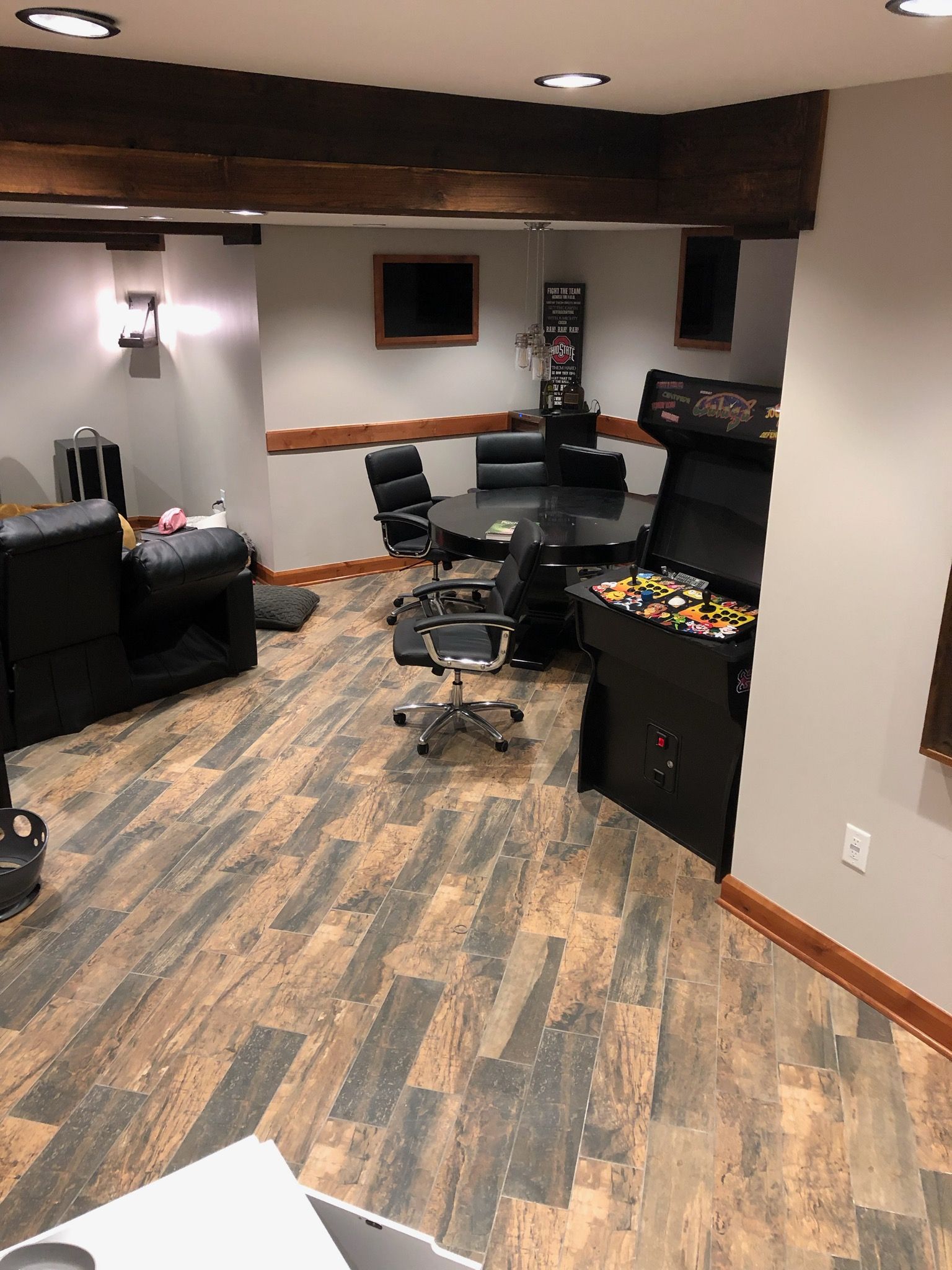 A basement with a table, chairs, and an arcade machine.