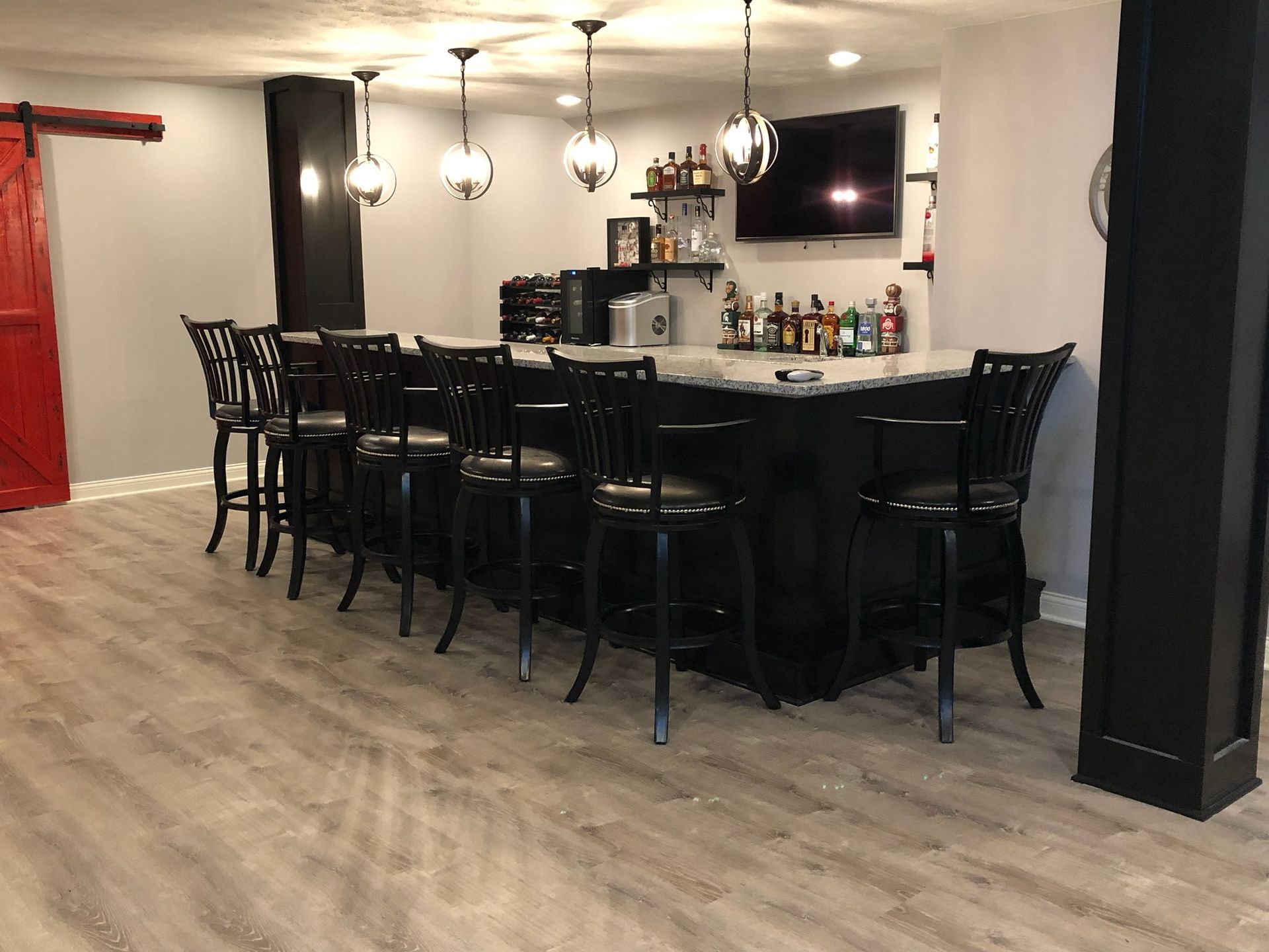 A bar in a basement with stools and a television.
