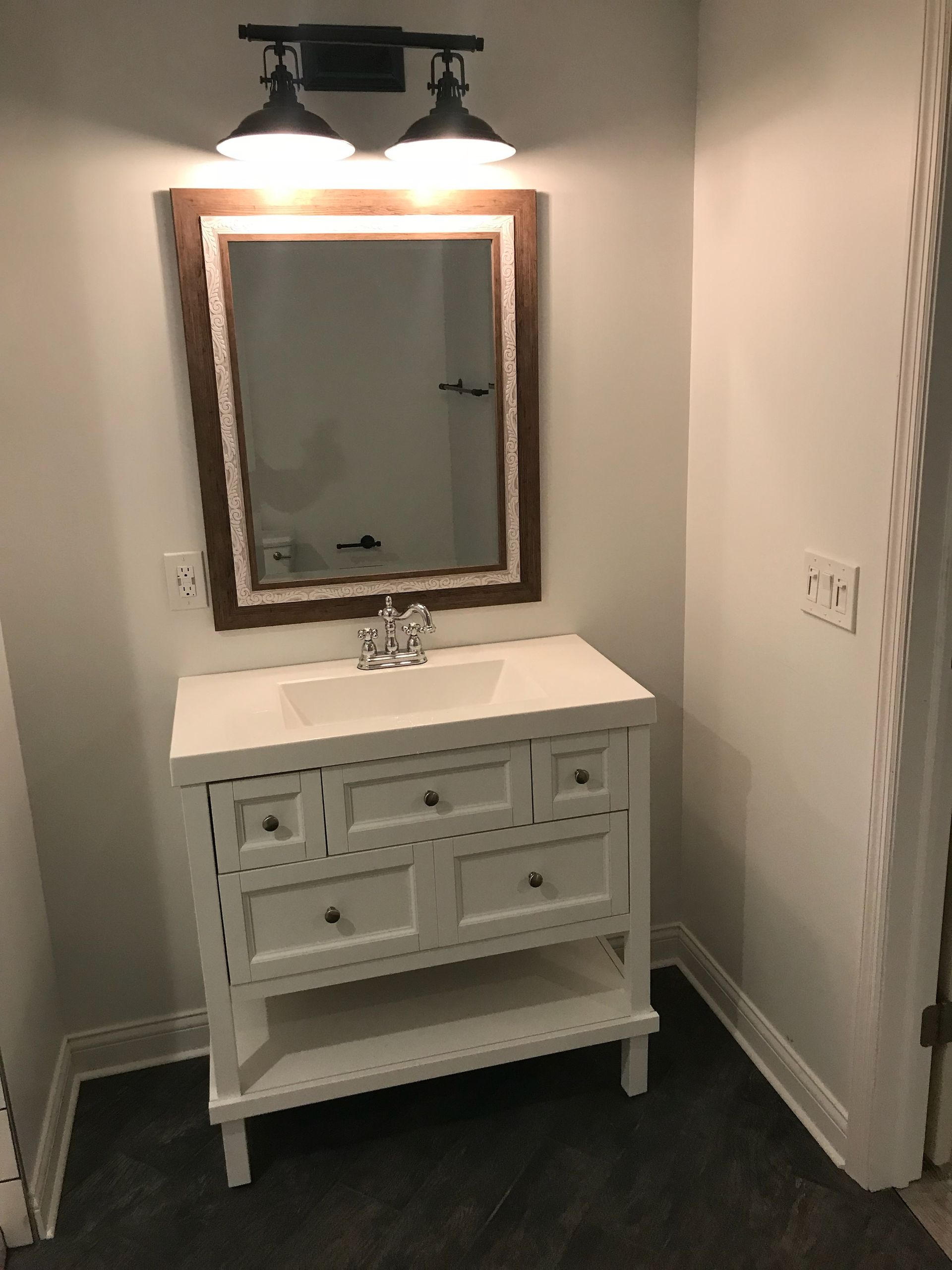 A bathroom with a sink, mirror and light fixture.
