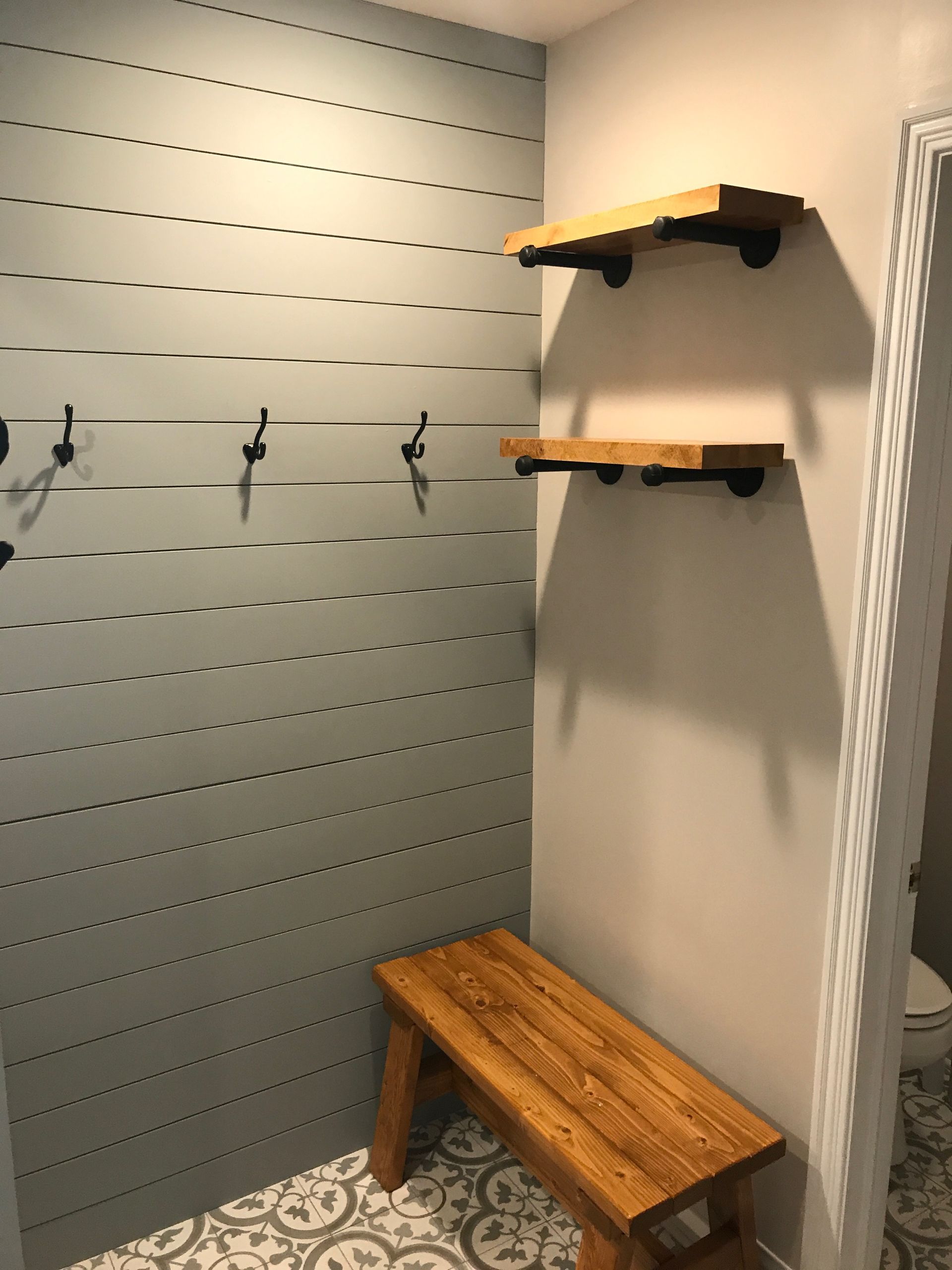 A hallway with a wooden bench and shelves.