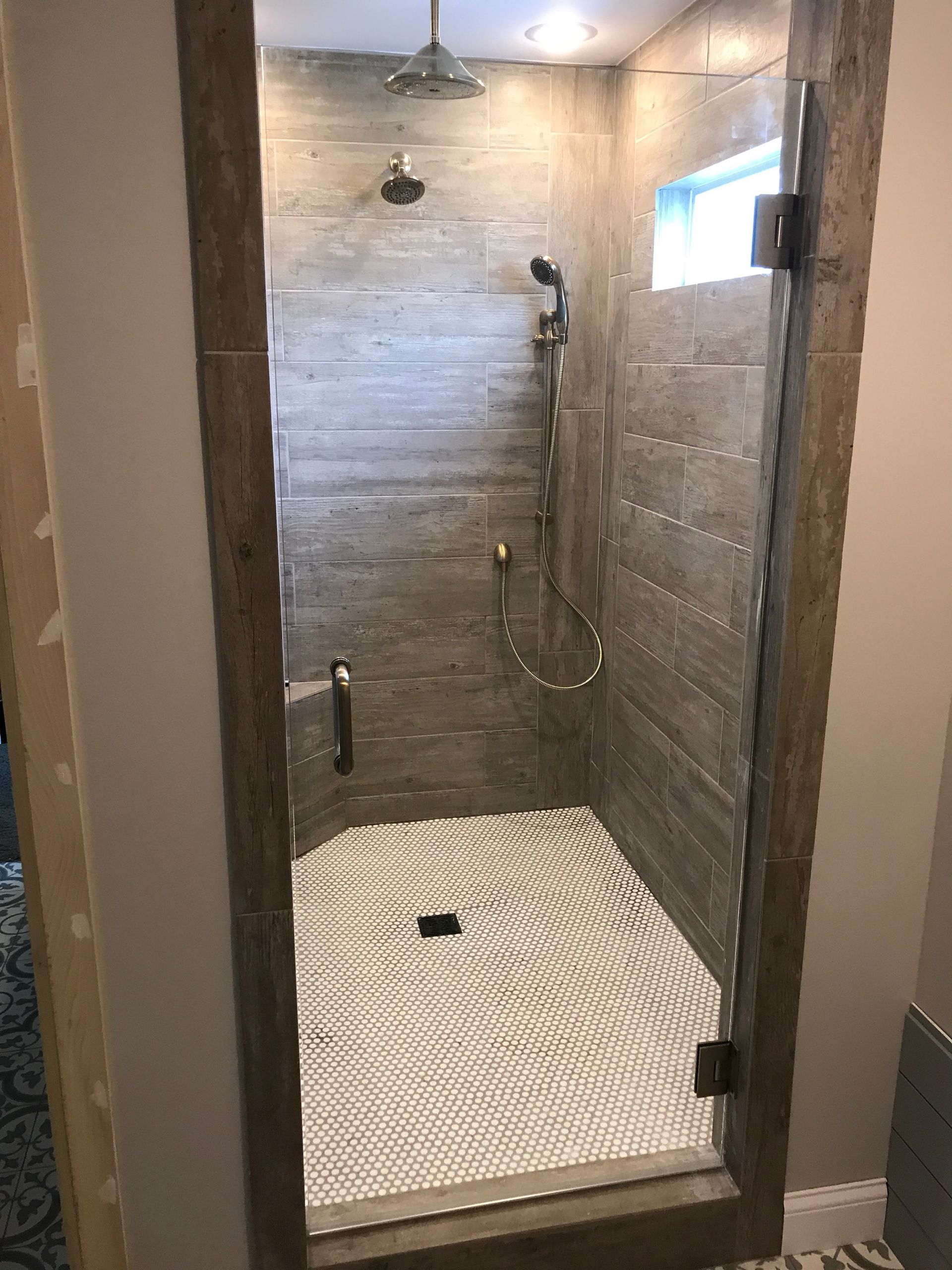 A bathroom with a walk in shower with a glass door.