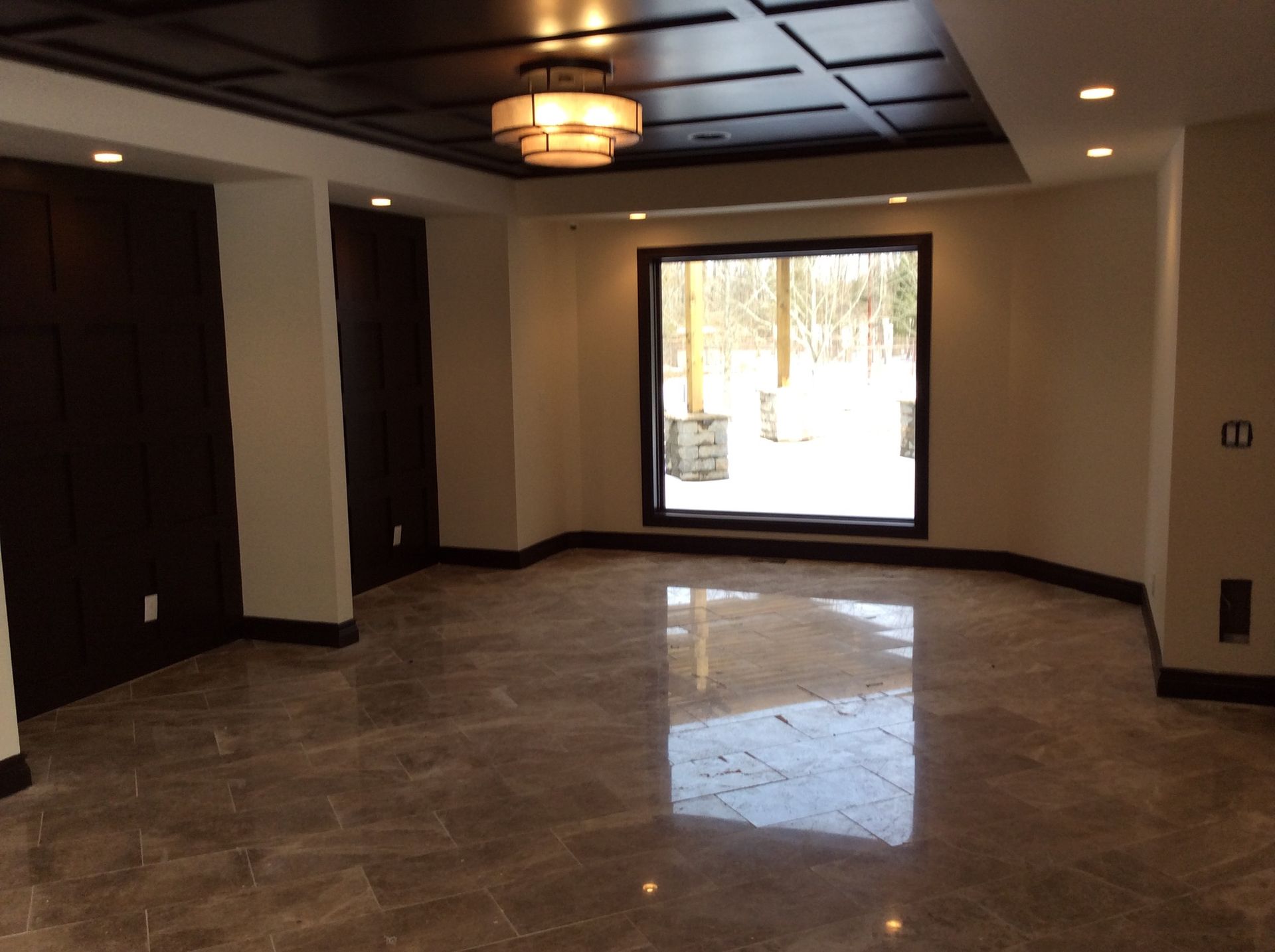 An empty room with a large window and a chandelier.