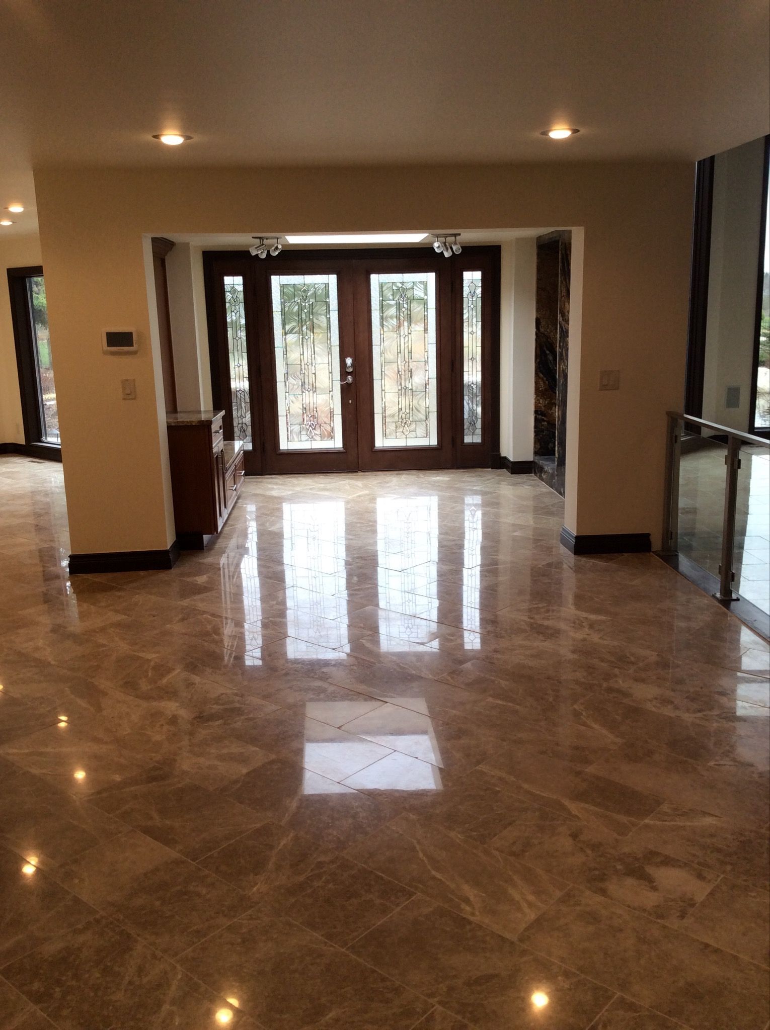 A large empty room with a marble floor and a wooden door.