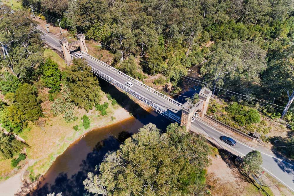 An Aerial View of a Bridge Over a River Surrounded by Trees — Illawarra Gardening Landscapes in Southern Highlands, NSW