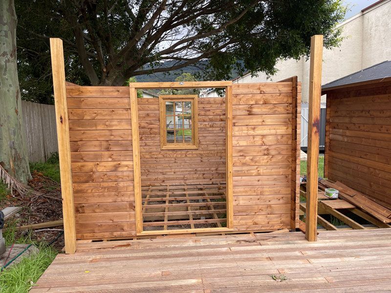 A Wooden Shed is Being Built in a Backyard With a Window — Illawarra Gardening Landscapes in Shellharbour, NSW