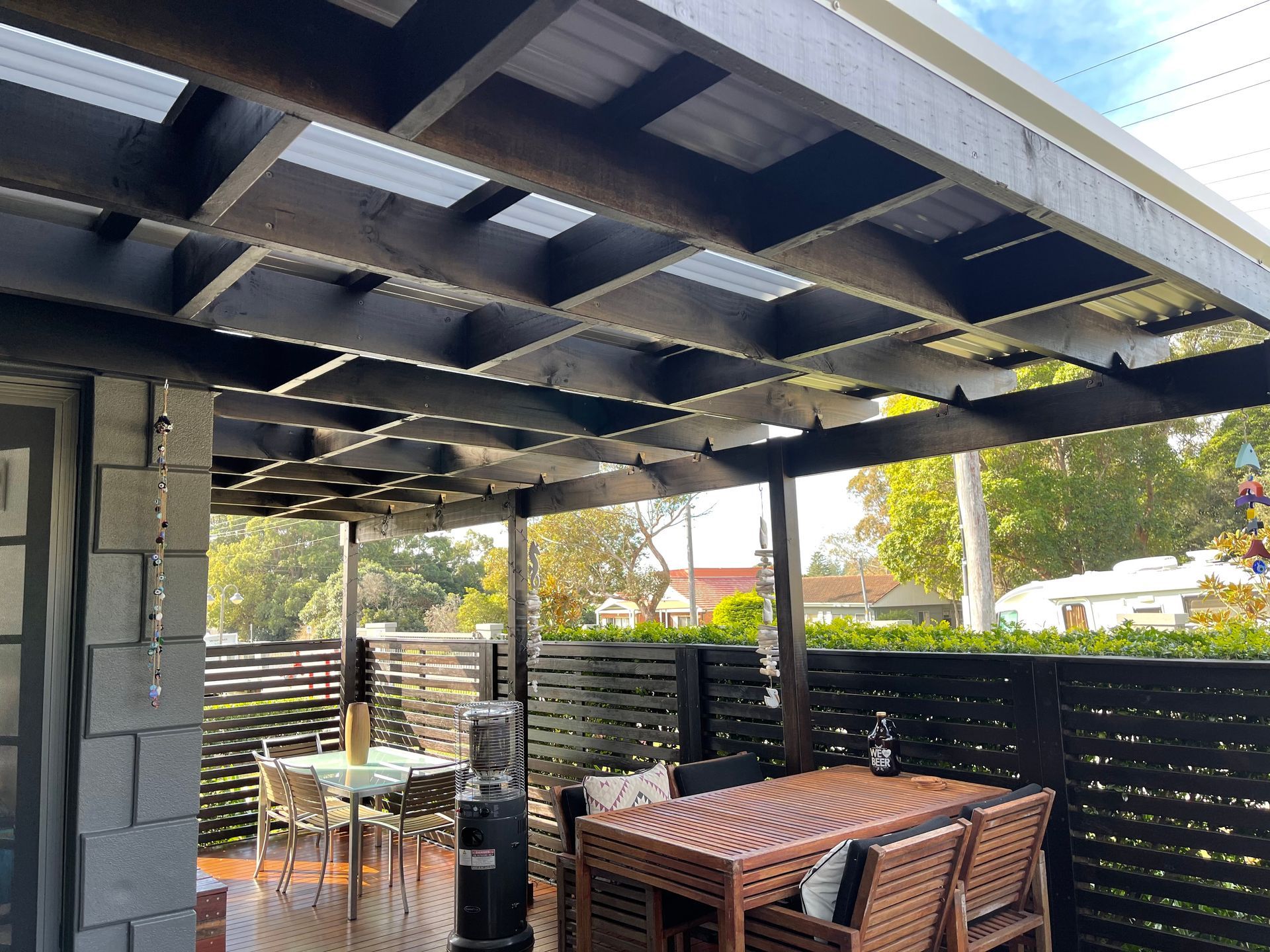 A Patio With a Table and Chairs Under a Pergola — Illawarra Gardening Landscapes in Blackbutt, NSW
