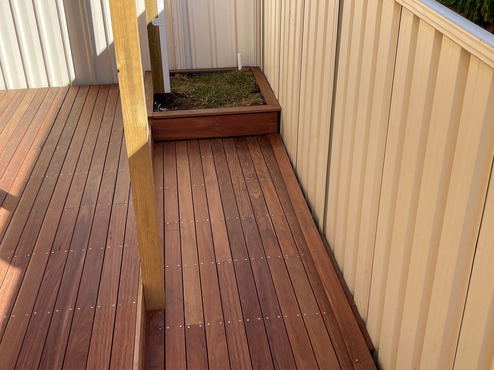 A Wooden Deck With a White Fence in the Background — Illawarra Gardening Landscapes in Blackbutt, NSW