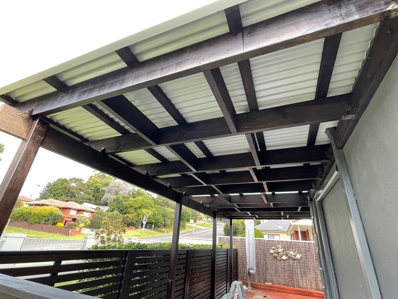 A Wooden Pergola With a White Roof is Sitting on Top of a House — Illawarra Gardening Landscapes in Shellharbour, NSW