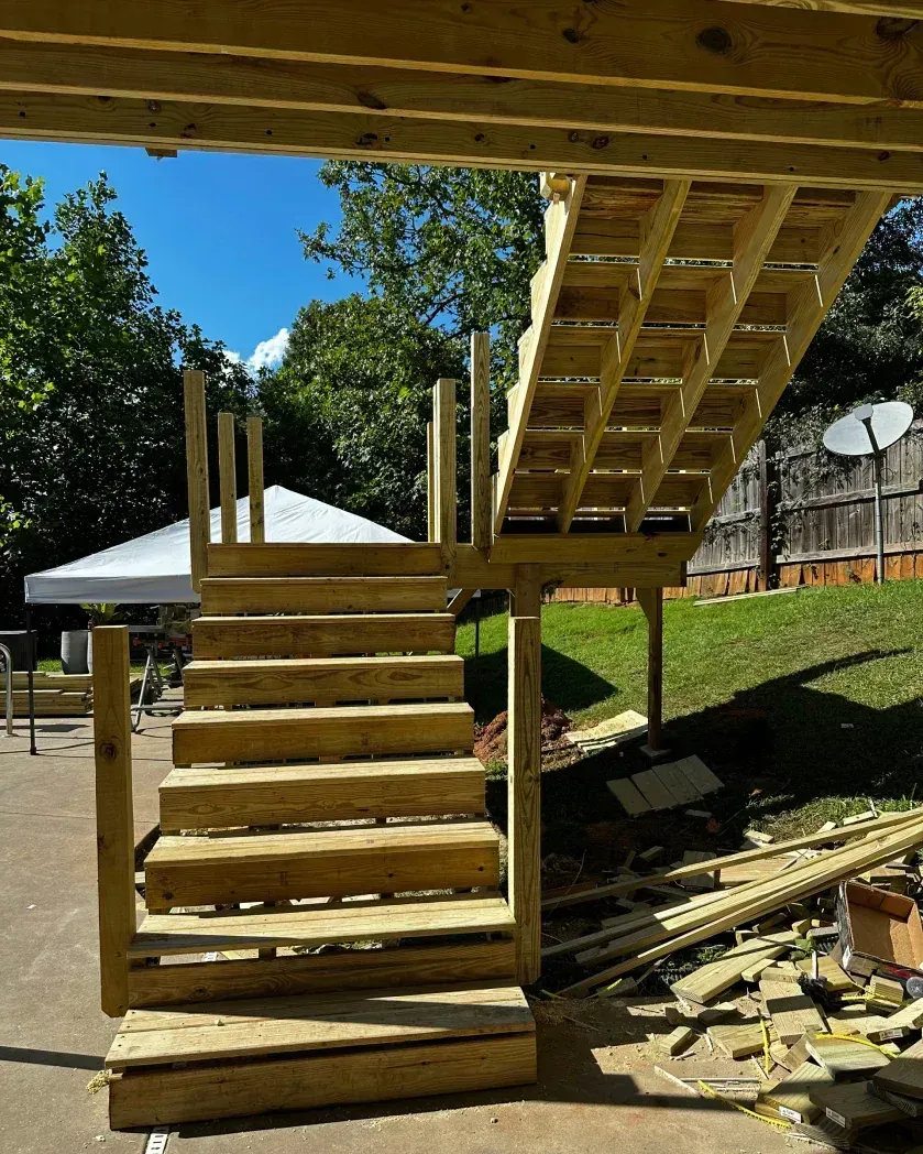 New wooden deck stairs under construction, with a lower set of steps leading to a platform and an upper flight above.