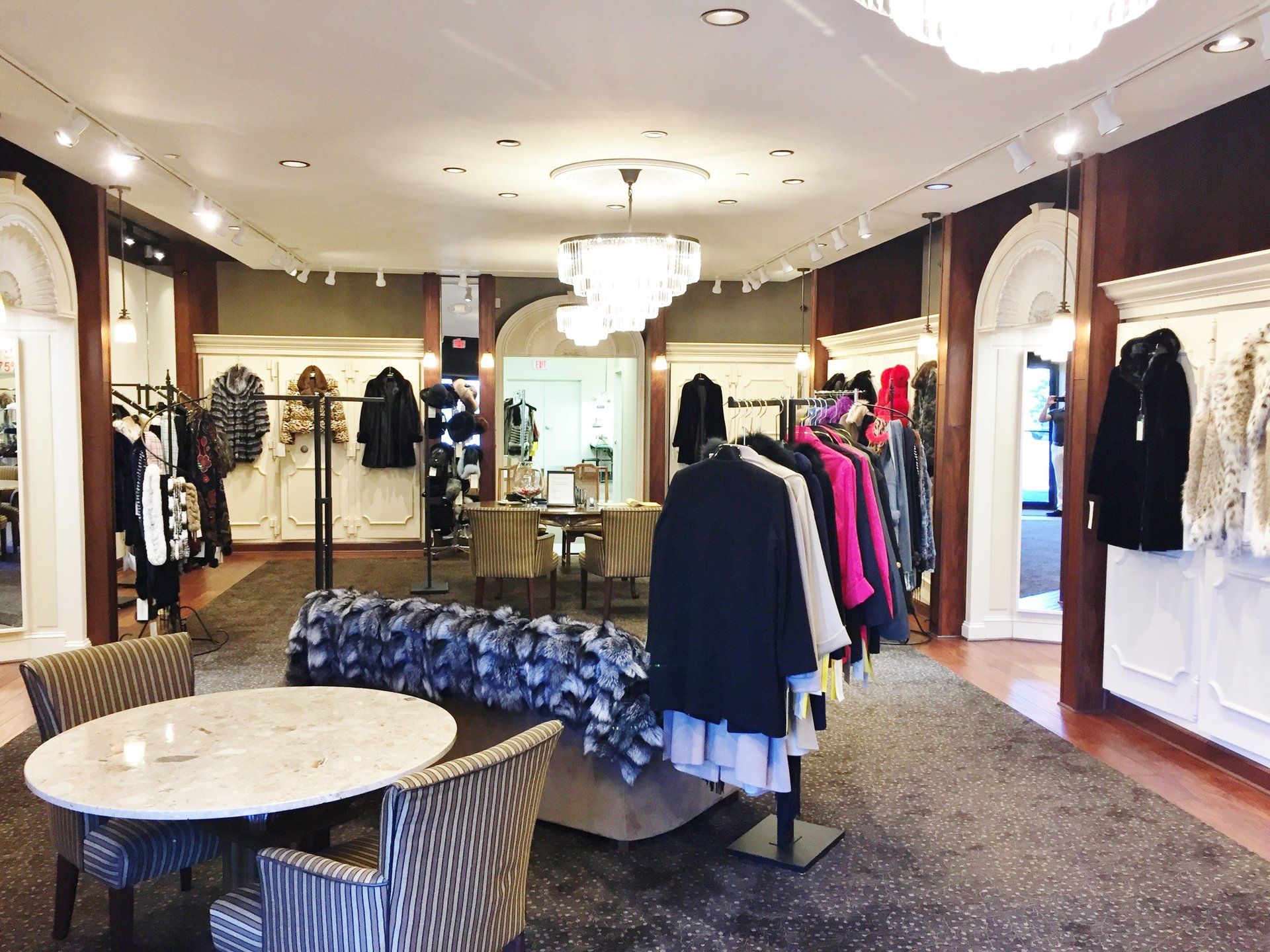 A clothing store with a table and chairs and clothes on display.