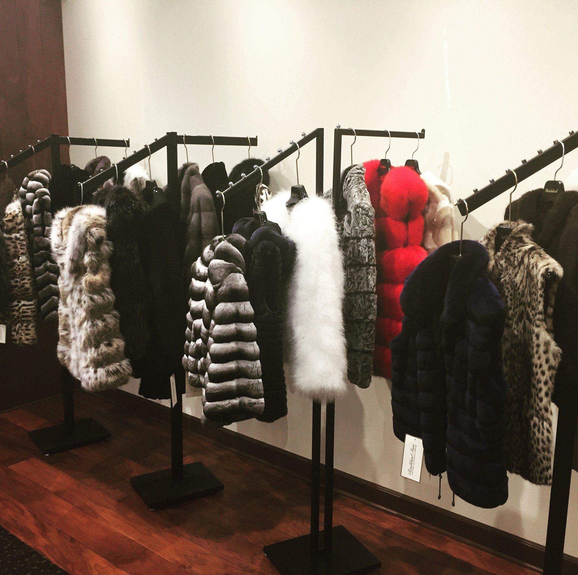 A row of fur coats hanging on racks in a store