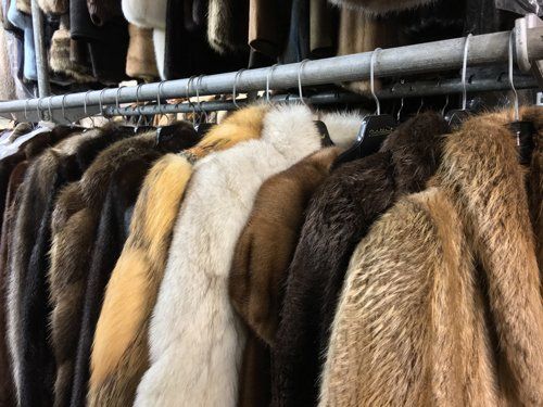 A row of fur coats hanging on a rack in a store.