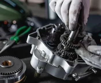 A person is working on a motorcycle engine in a garage.