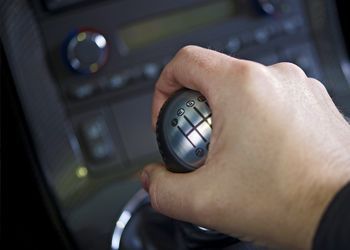 A close up of a person 's hand holding a gear shift in a car.