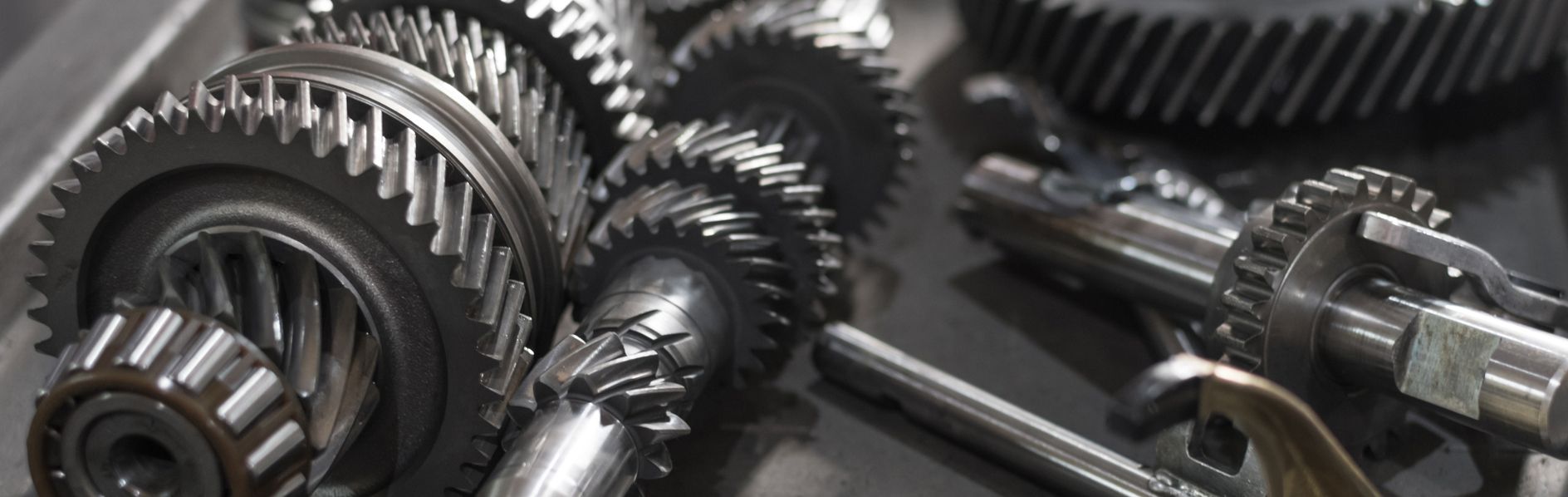 Gears and other metal parts in a mechanic's workshop, likely components of a machine or vehicle's transmission.