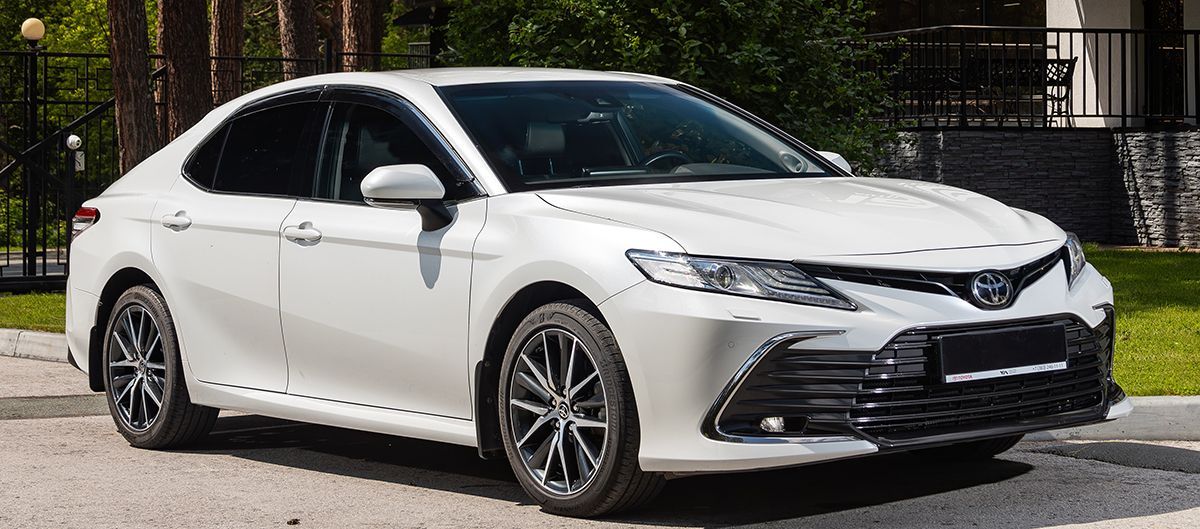 White Toyota Camry sedan parked on a paved driveway.