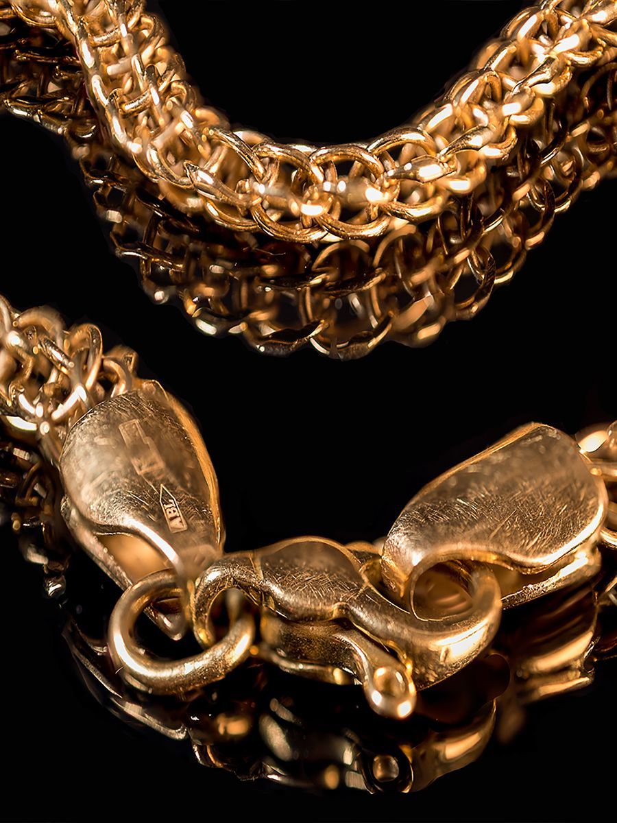 Gold chain with a clasp against a black background.