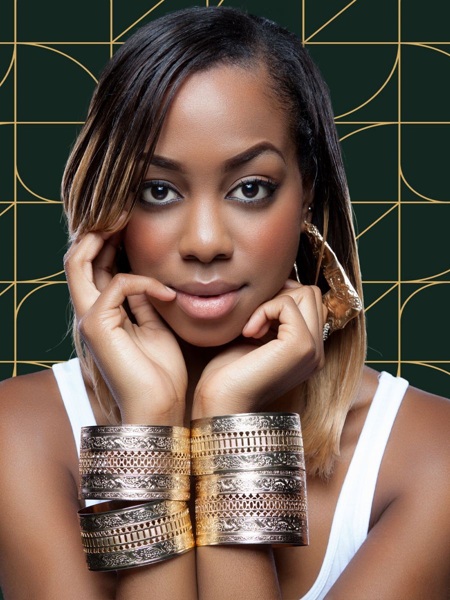 Woman with gold jewelry, hands near face, gazing at the viewer. Against a dark background with gold geometric shapes.
