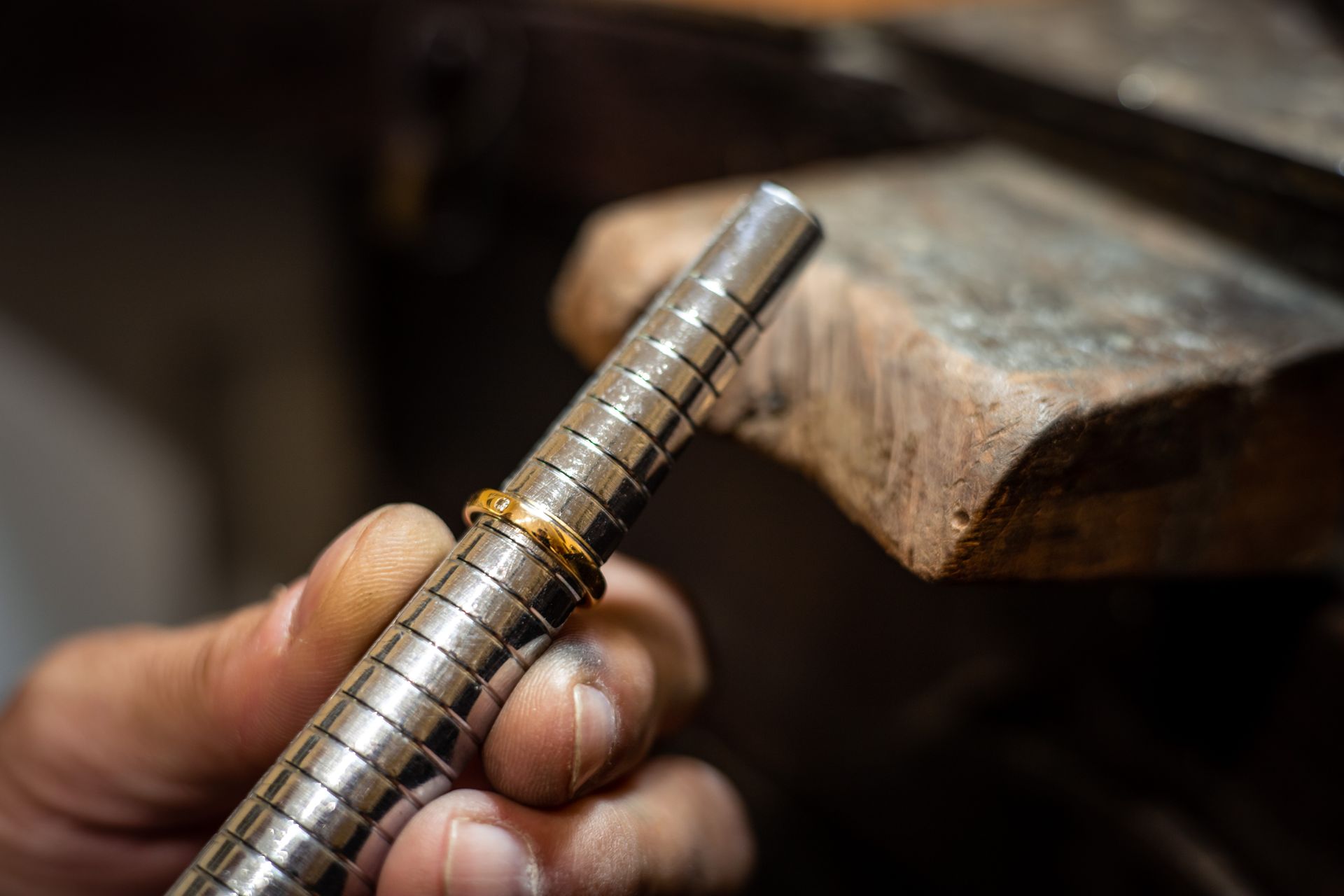 Close-up of a jeweler measuring a gold ring on a sizing tool.