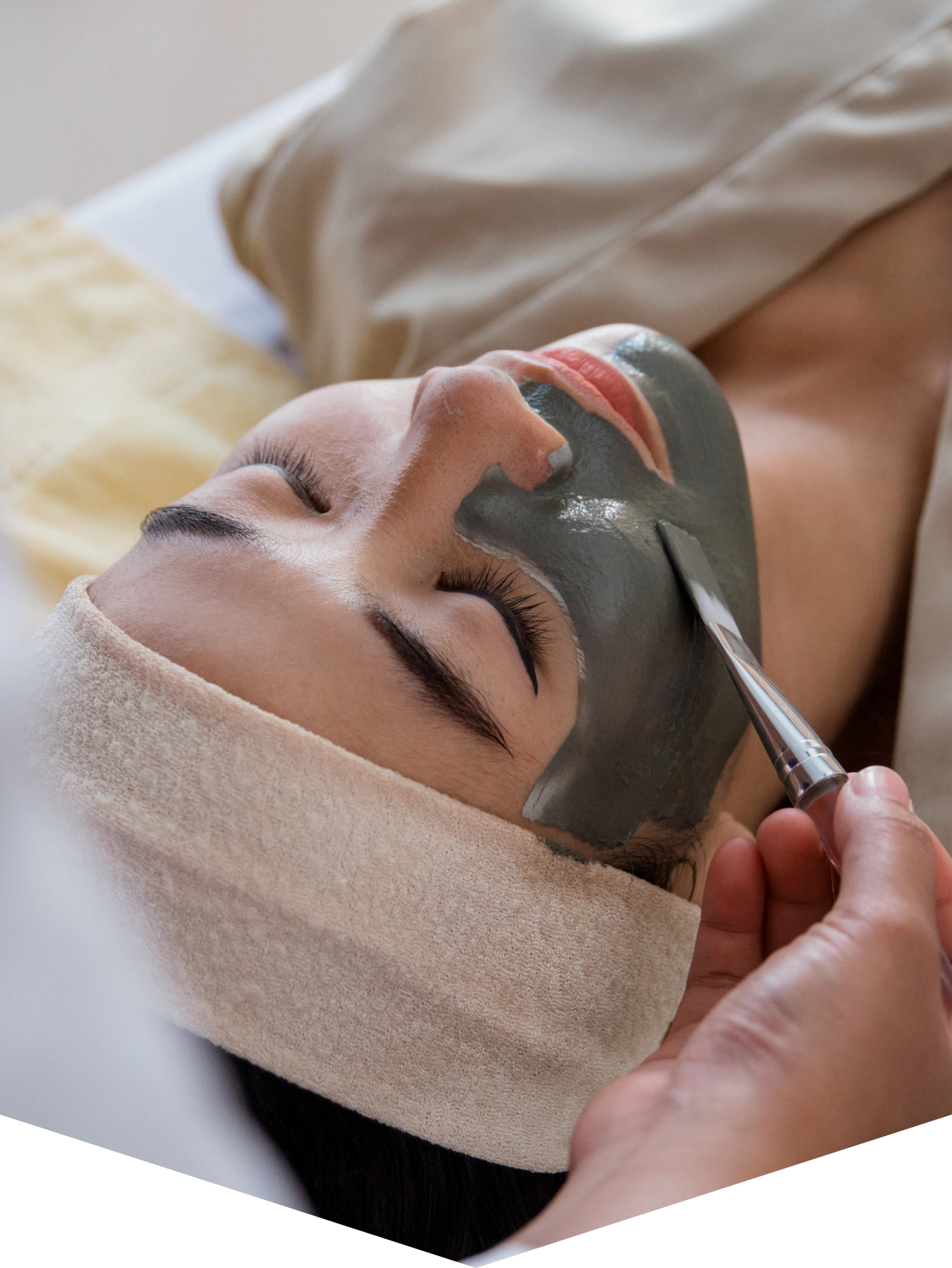 Eine Frau bekommt eine Gesichtsbehandlung mit einer Maske im Gesicht.