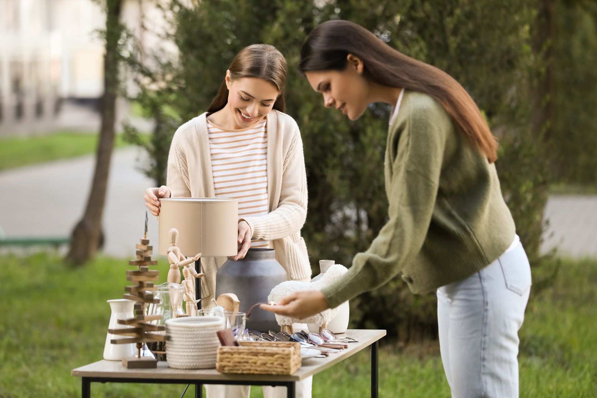 Two women are standing next to a table with a lamp on it.