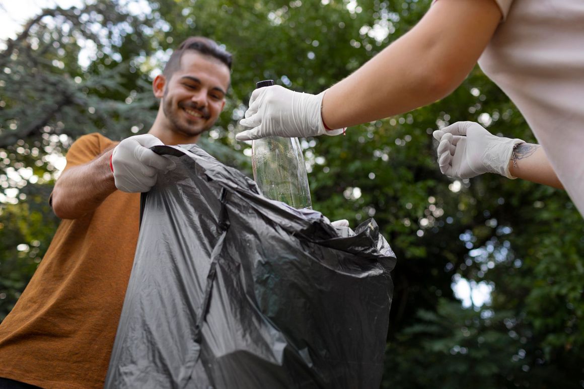 A man and a woman are picking up trash in a park.