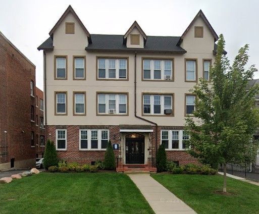 Mid-Century apartment building with green grass and a large tree