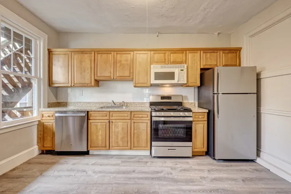 Kitchen with light wood cabinets, stainless steel appliances, and a window.