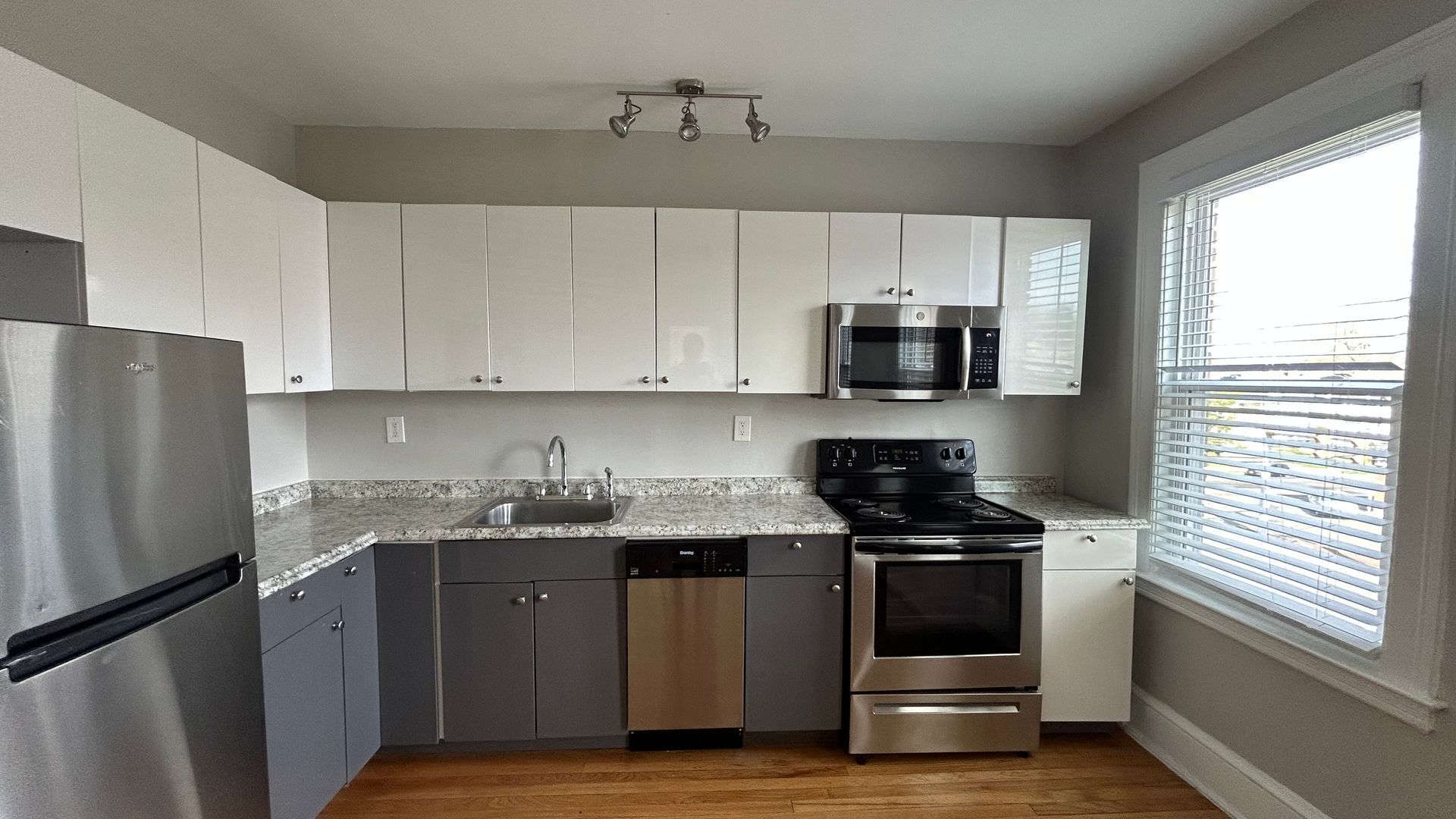 Renovated kitchen with white cabinets , hardwood flooring, and stainless steel appliances