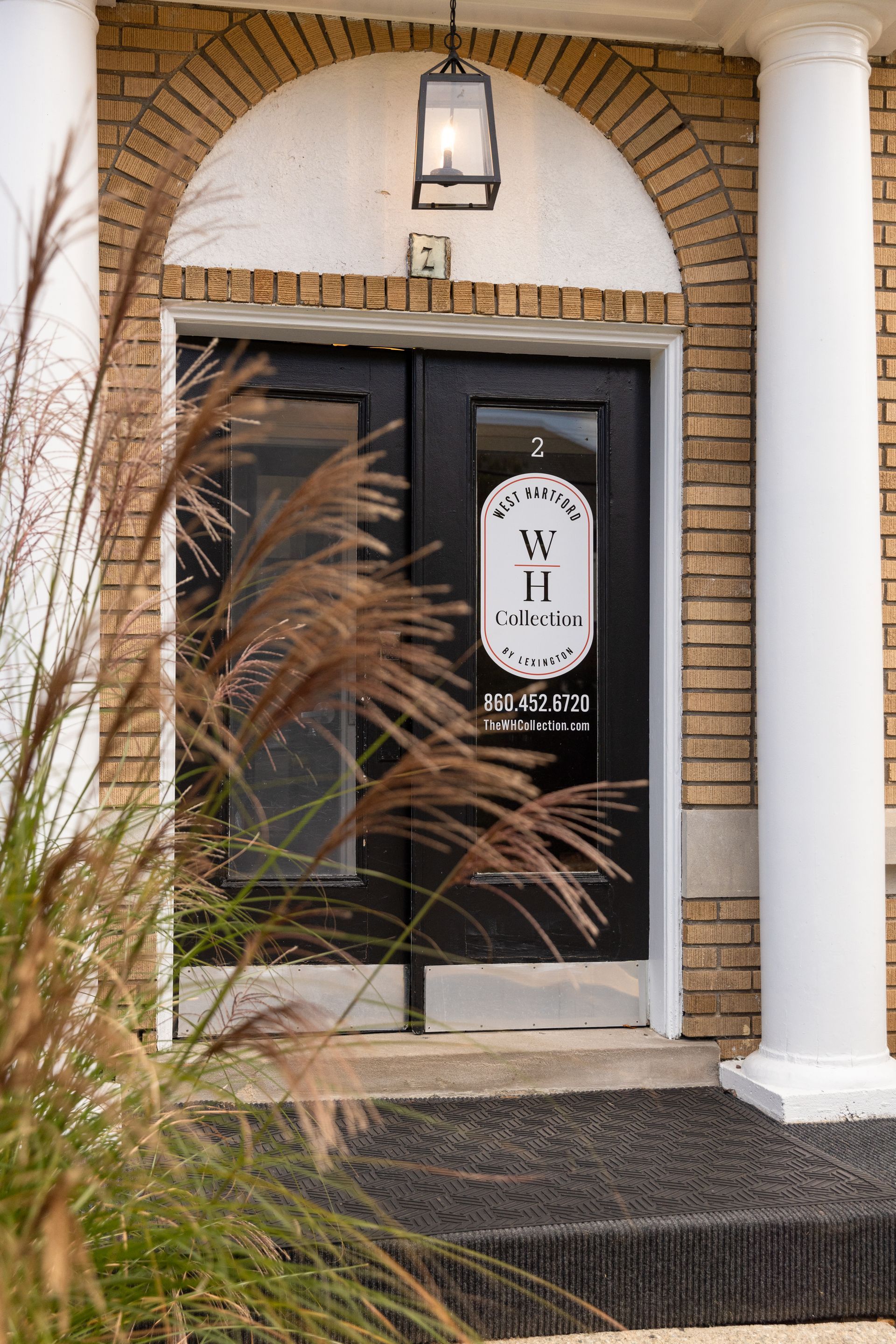 Black doors with a white arched frame and white columns. Sign: 