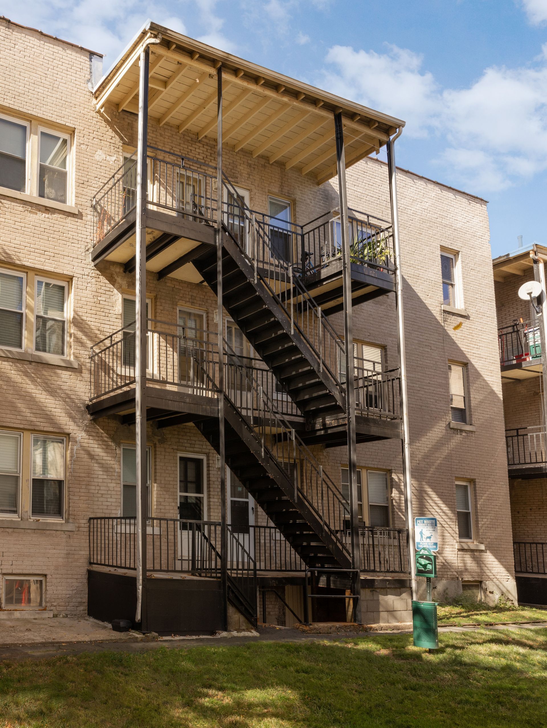 Black fire escape on brick building, with a covered top landing.