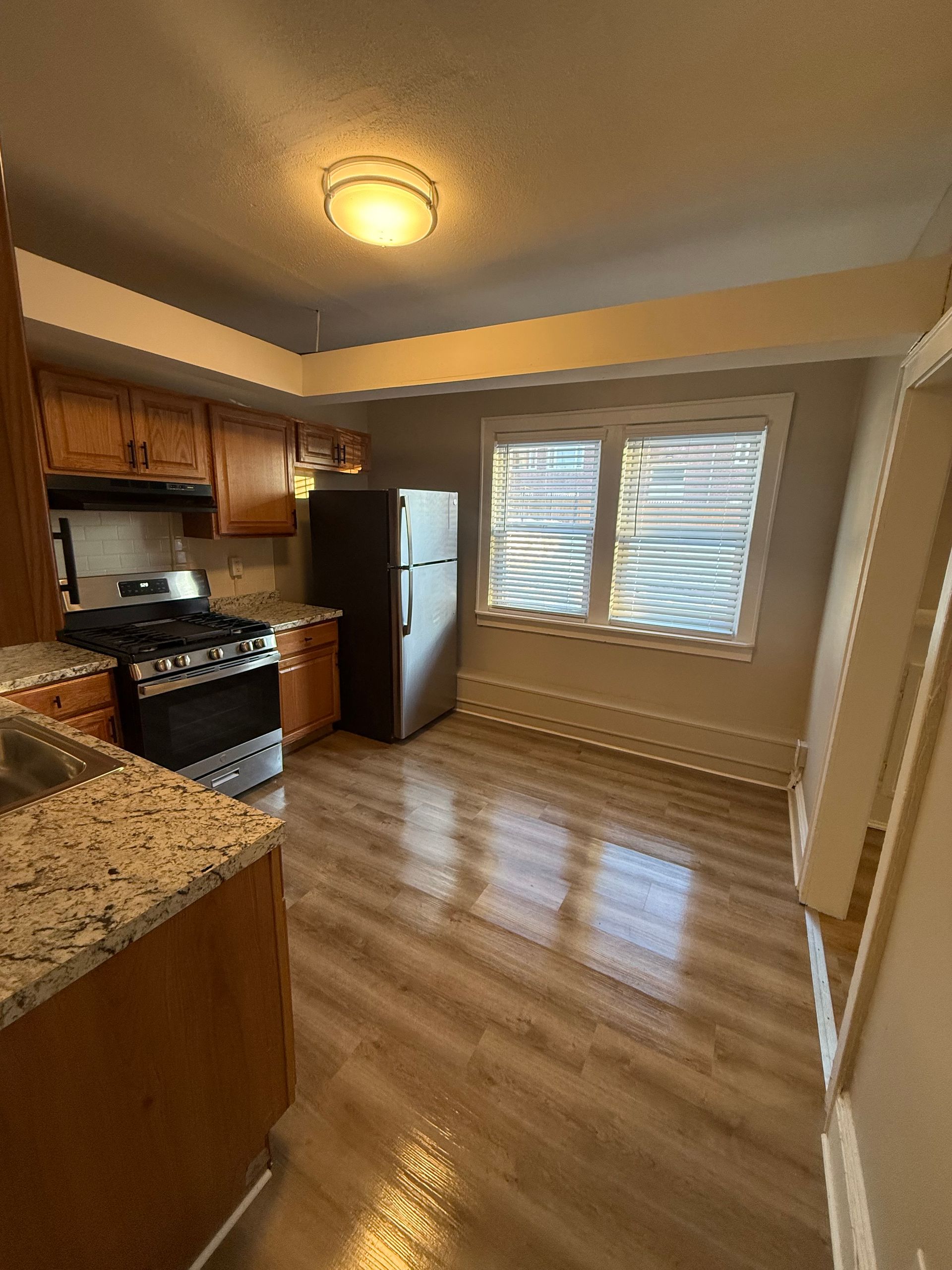 Renovated kitchen with wood cabinets, flooring, and stainless steel appliances