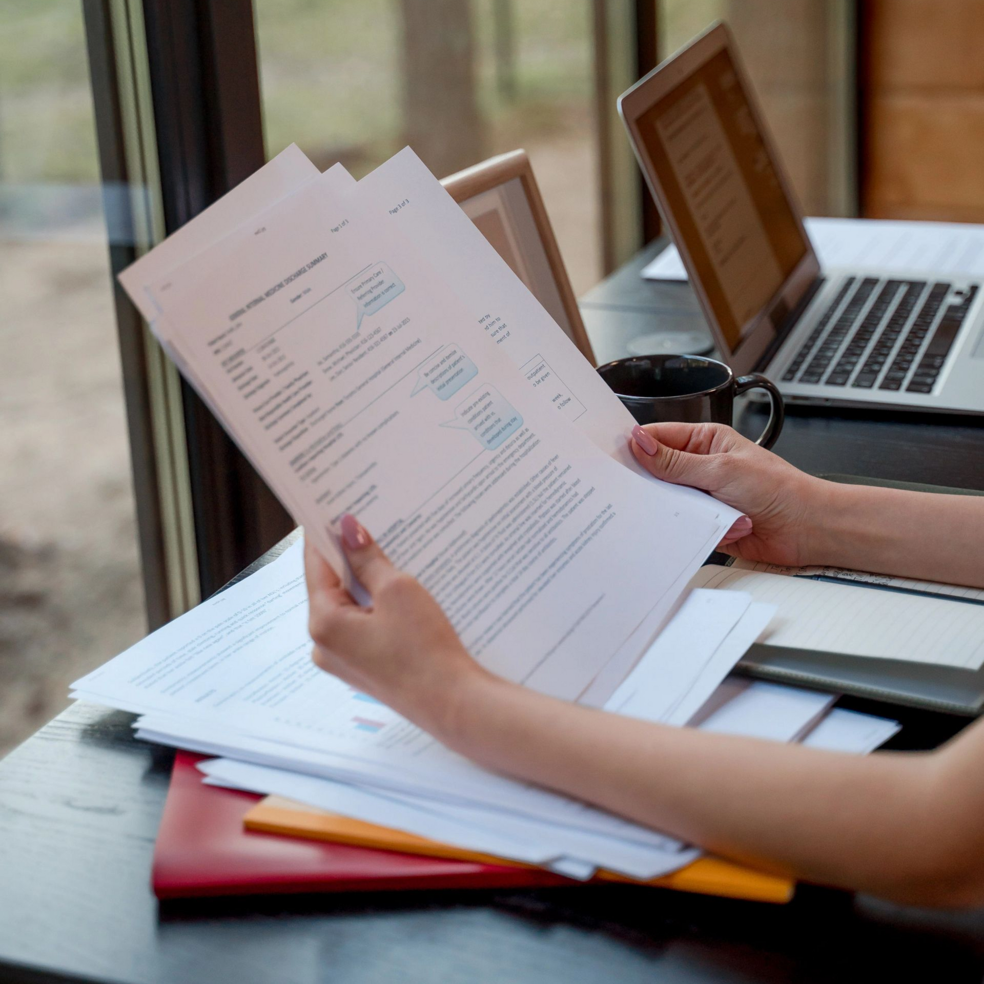 Person holding papers next to a computer