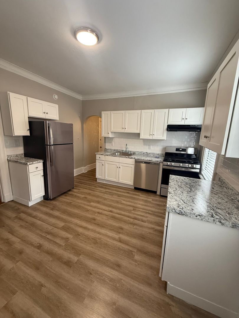 Renovated kitchen with white cabinets, hardwood flooring stainless steel appliances