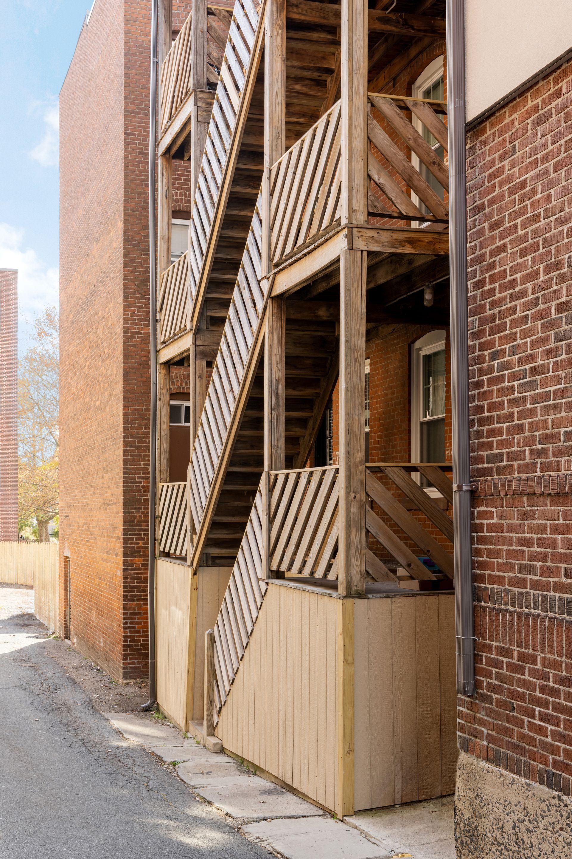 Wooden exterior stairwell between brick buildings.