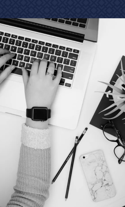 A person wearing a watch is typing on a laptop